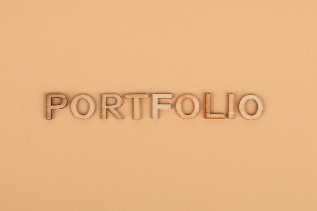 Close-up of wooden letters spelling 'PORTFOLIO' on a yellow background, offering creative copyspace.
